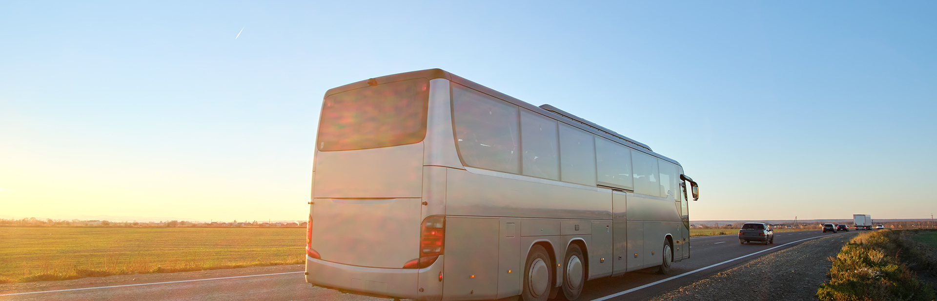 Intercity passenger bus driving on highway in evening.